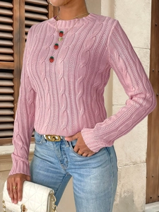 Close-up of pink cable knit texture and unique strawberry pendants on a crewneck sweater