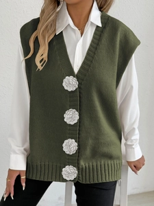 Detail of dark green knit vest with 3D white crochet flower buttons and V-neckline