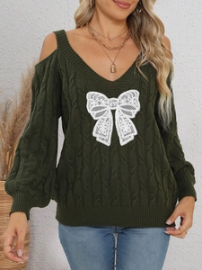 Close-up of cable knit dark green sweater featuring white lace bow and cold shoulder cutouts