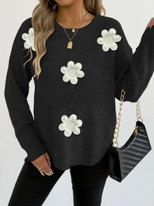 Detailed close-up of black knitted sweater featuring elegant white 3D floral appliques