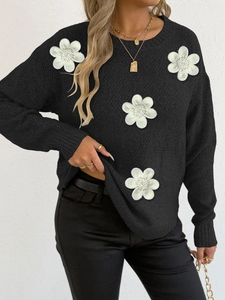 Detail of black knit sweater featuring 3D white floral appliqués with bead centers