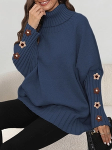 Detail of blue turtleneck sweater showing intricate brown floral embroidery on the sleeve cuff