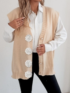Detail of beige knit vest featuring pearl buttons and delicate 3D crochet rose applique