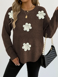 Detailed close-up of brown knit sweater featuring 3D white floral patches and texture