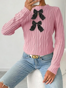Detail view of pink cable knit sweater featuring large black satin bows and slim fit texture