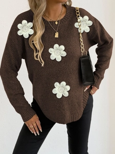 Close-up of 3D white knitted flowers and beadwork on a dark brown sweater top