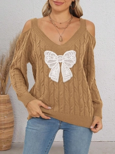 Close-up of ginger cable-knit sweater featuring white lace bow and cold shoulder cutouts