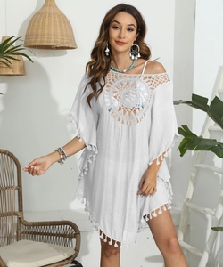 Détail d'une tunique de plage blanche bohème avec col en crochet et finitions à pompons