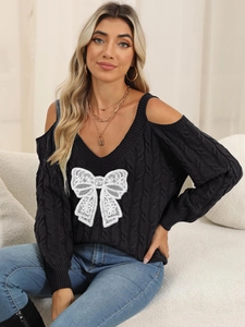 Detail of cable knit sweater with cold-shoulder design and white lace bow decoration