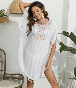 Détails de l'encolure en crochet et des franges sur cette robe de plage blanche