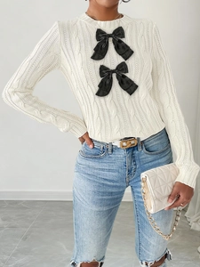 Detail of cable knit texture and black bow accents on an elegant ivory sweater