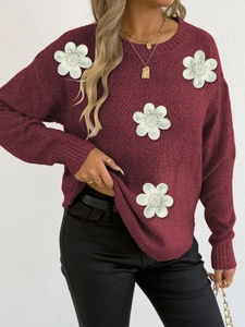 Detail of burgundy knit sweater featuring 3D crochet white flowers and pearl bead accents