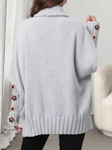 Detail view of light blue-grey chunky knit sweater featuring 3D floral crochet on sleeves