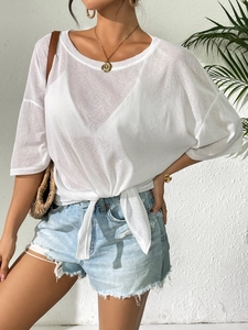 Detail of white semi-transparent top with knotted hem and distressed denim shorts