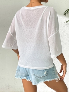 Detail of white sheer off-shoulder top with tie-knot and frayed denim shorts set