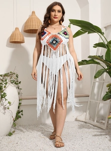 Detail of colorful hand-crocheted diamond patterns and long tassels on white beach dress