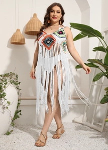 Detail of white crochet beach cover-up featuring colorful diamond patterns and long tassels