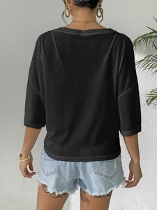 Detail of the back view of a black loose-fit blouse with drop shoulders and a casual style
