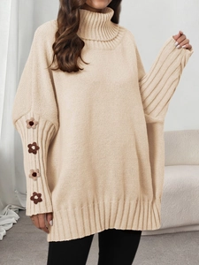 Detailed view of hand-crocheted floral patches on sleeves of beige turtleneck knit sweater
