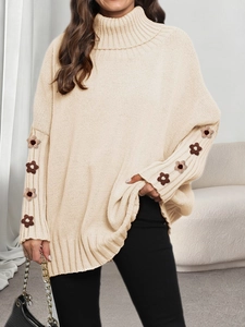 Detail of beige oversized turtleneck sweater featuring brown 3D crochet floral sleeve patches