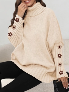 Detail of crochet flower stitching on sleeves of a beige turtleneck knit sweater