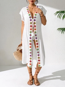 Detail of white beach cover-up featuring colorful crochet embroidery and ruffled sleeves