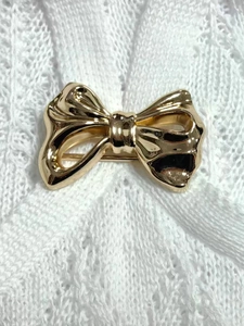 Detail einer glänzenden goldenen Schmetterlingsschleife auf weißem Spitzenstoff