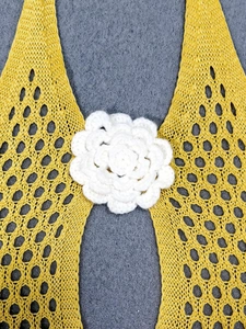Detail of yellow crochet knit halter top with 3D white floral center ornament