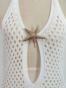 Detail of white crochet halter neck top featuring a decorative golden starfish metal charm