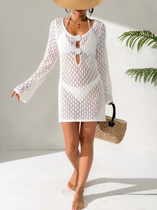 Close-up of white crochet beach cover-up with detailed floral accents and knit textures