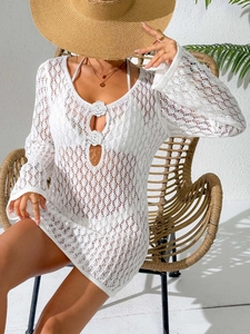 Detail of white crochet beach cover-up featuring 3D floral accents and wavy knit patterns