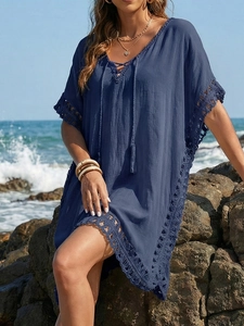 Detail of navy blue beach cover-up featuring V-neck lace-up design and crochet tassels