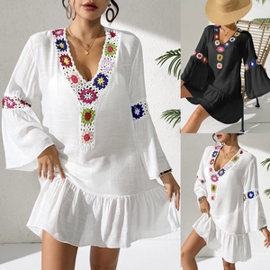 Close-up of bohemian V-neck dress with colorful hand-crocheted floral details and flared sleeves
