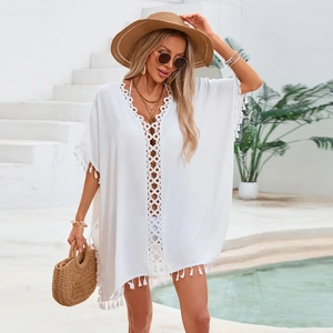Détail des finitions en crochet blanc ajouré et pompons sur ce vêtement de plage