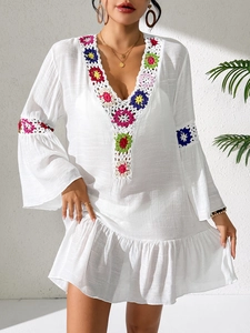 Close-up of bohemian white dress featuring colorful handmade crochet floral details