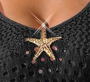 Detail of gold starfish metal hardware on a black mesh dress with textured finish