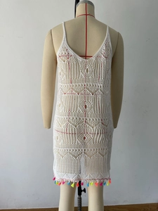 Detail of white crochet beach cover-up with hollow knit patterns and colorful fringe hem