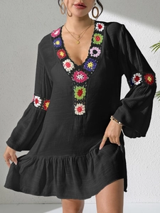 Detail of colorful crochet flowers on black V-neck bohemian beach dress with ruffled sleeves