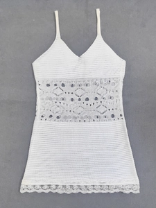 Detail of white crochet hollow-out lace and intricate knit patterns on a summer camisole