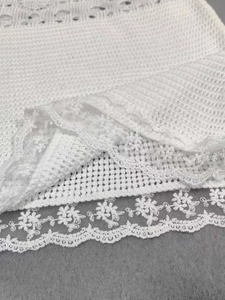 Detail shot of the white knitted lace hem with floral embroidery on the beach dress