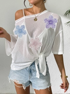 White off-shoulder beach blouse with colorful floral patches and waist tie detail