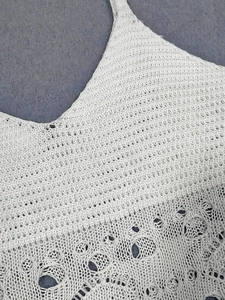 Detail of white knit lace beach dress with intricate crochet patterns and hollow out design