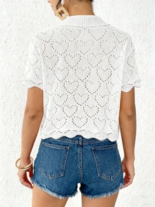 Women's white crochet cardigan with heart patterns and denim shorts back view