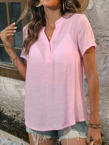 Détail d'un chemisier rose à col Henley en tissu texturé avec des boutons blancs
