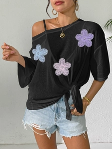 Women's black one-shoulder top with floral embroidery and side tie knot detail