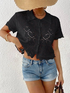 Detail of black knit cardigan with heart openwork pattern and classic polo collar design