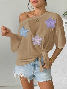 Detail of sheer mesh top with 3D floral appliques and side tie-knot waist detail