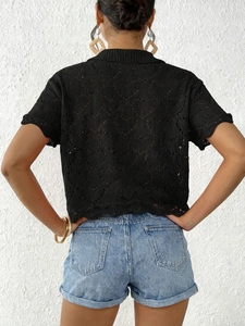 Detail of black openwork knit top featuring diamond crochet patterns and scalloped hem