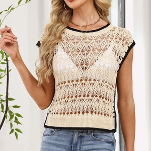 Detail of hollow-out knit pattern with contrast black trim on a cream crochet vest top