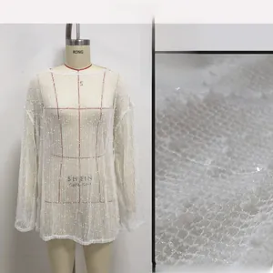 Détail de la tunique en maille blanche avec paillettes discrètes et texture brillante